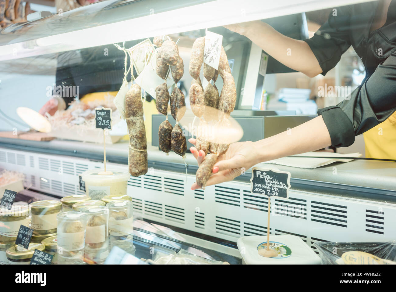 Fille dans les ventes au comptoir des viandes de charcuterie fine certaines saucisses Banque D'Images