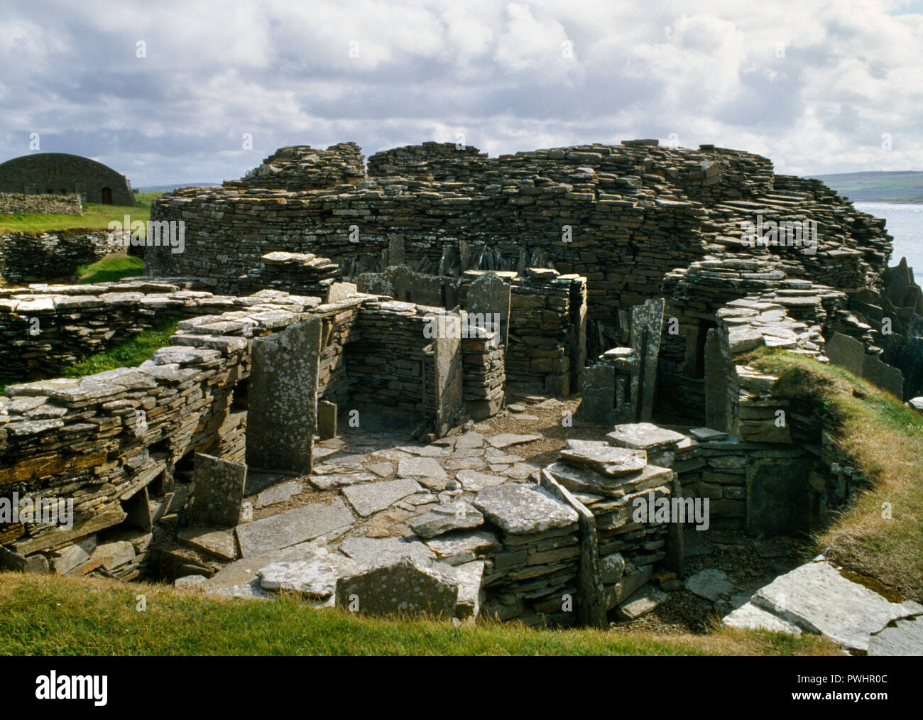 Voir s de maisons construites plus tard autour de Midhowe broch de l'âge du Fer (centre arrière de la tour) sur la côte sud de l'île de Rousay, Orkney, Scotland, UK. Banque D'Images