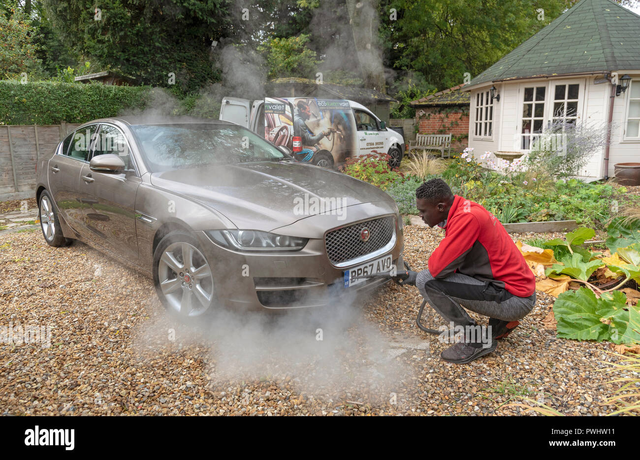 Nettoyage à la vapeur de l'homme l'extrémité avant d'une voiture de luxe sur de visites à domicile, un service de valet, England UK Banque D'Images