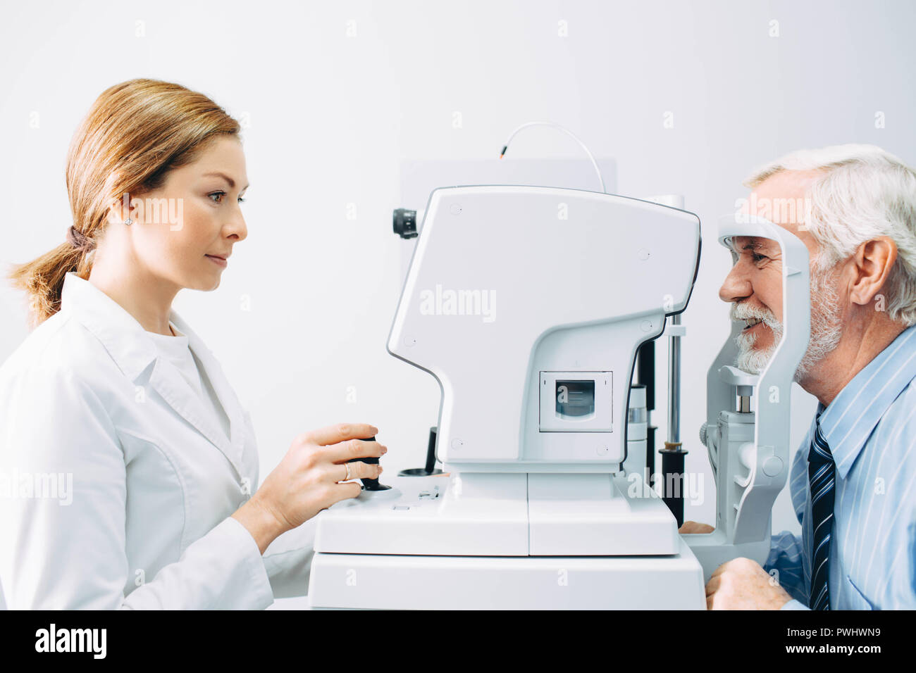 Docteur optométriste examinant les yeux du vieil homme avec un équipement oculaire spécial Banque D'Images