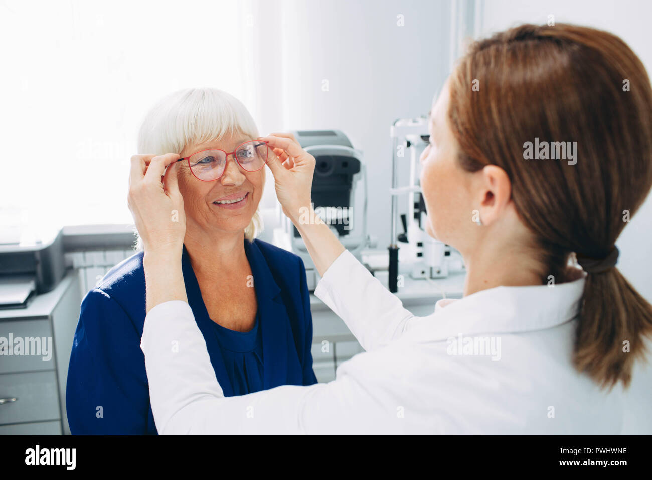 Happy senior femme essayant de nouvelles lunettes de lecture au bureau de l'opticien Banque D'Images