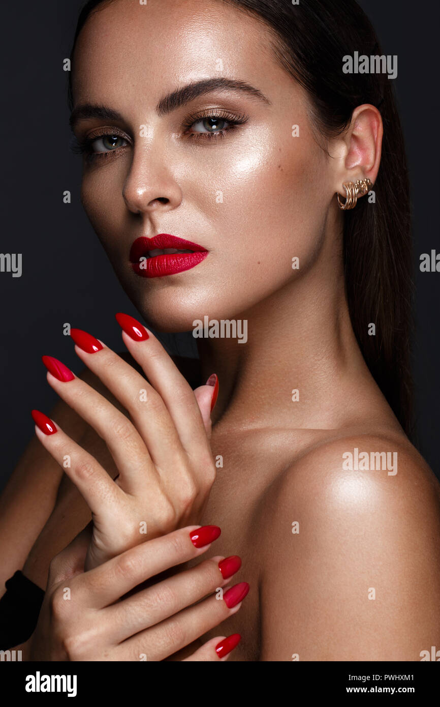 Belle fille avec un classique le maquillage et les ongles rouges. Conception de manucure. Beauté Visage. Banque D'Images