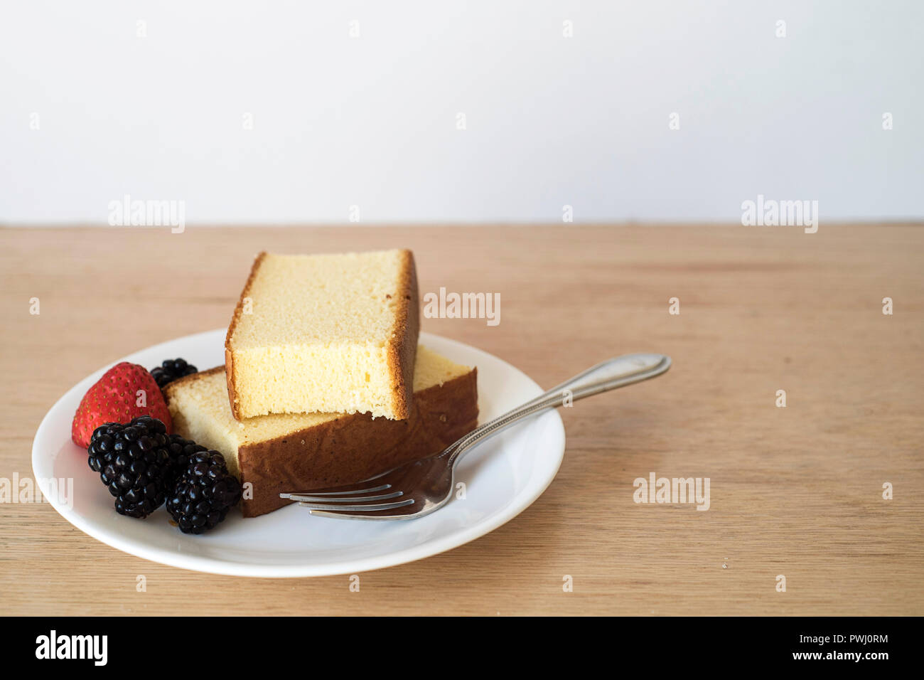 Morceaux de gâteau Castella avec des baies prêtes à manger dans un cadre lumineux Banque D'Images