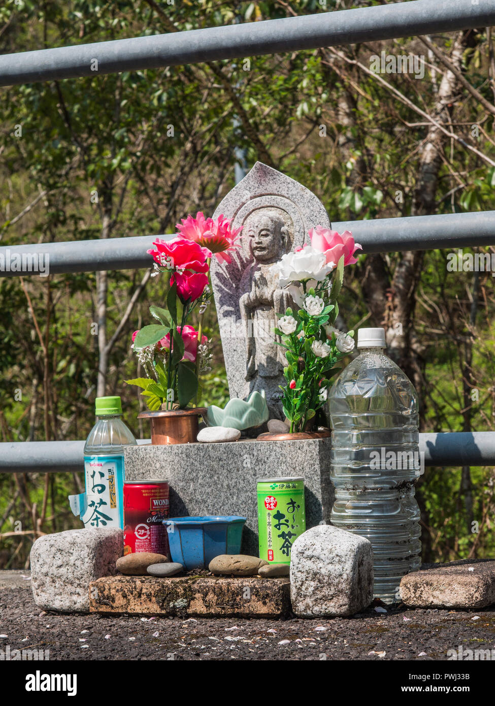Route de culte, une statue bouddhiste avec des fleurs en plastique, des offrandes de cailloux, boissons, Shimanto, Kochi, Shikoku, Japon Banque D'Images