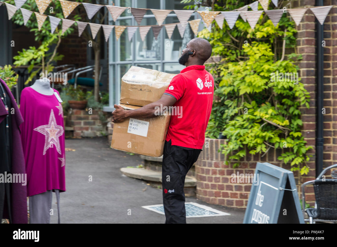 Chauffeur de livraison DPD de porter de lourds colis à un client dans le West Sussex, Angleterre, Royaume-Uni. Les livraisons de colis courrier britannique. Banque D'Images