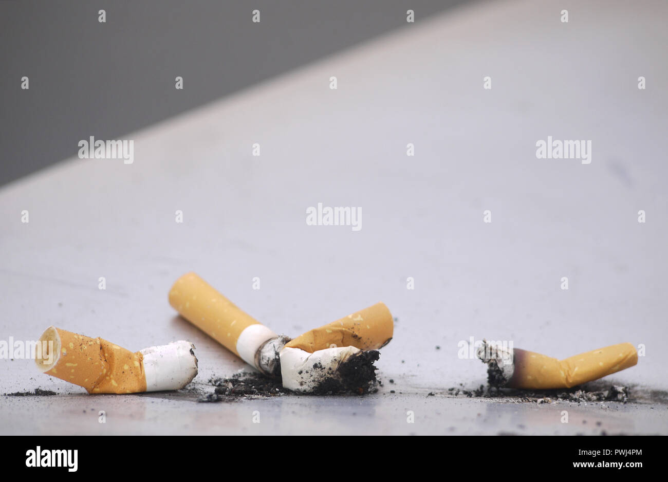 Utilisé sur la surface de métal cigarettes jetées avec ash Banque D'Images