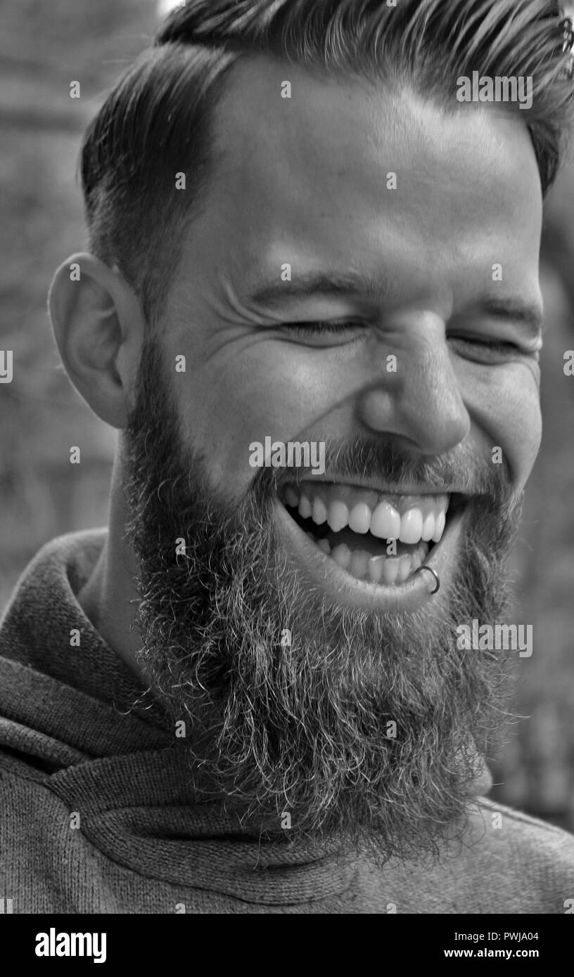 Jeune homme à la barbe en riant très fort. Banque D'Images