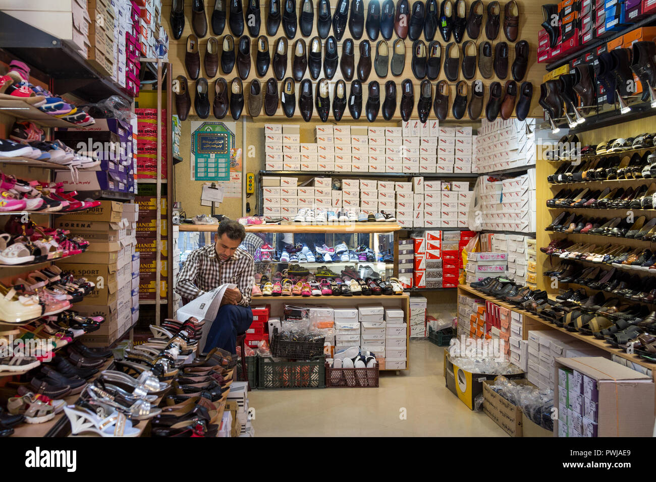 YAZD, IRAN - le 18 août 2016 : Ancien commerçant iranien chaussures vente reading newspaper in Farsi à Yazd Khan bazar. Yazd est l'une des principales villes de la cen Banque D'Images