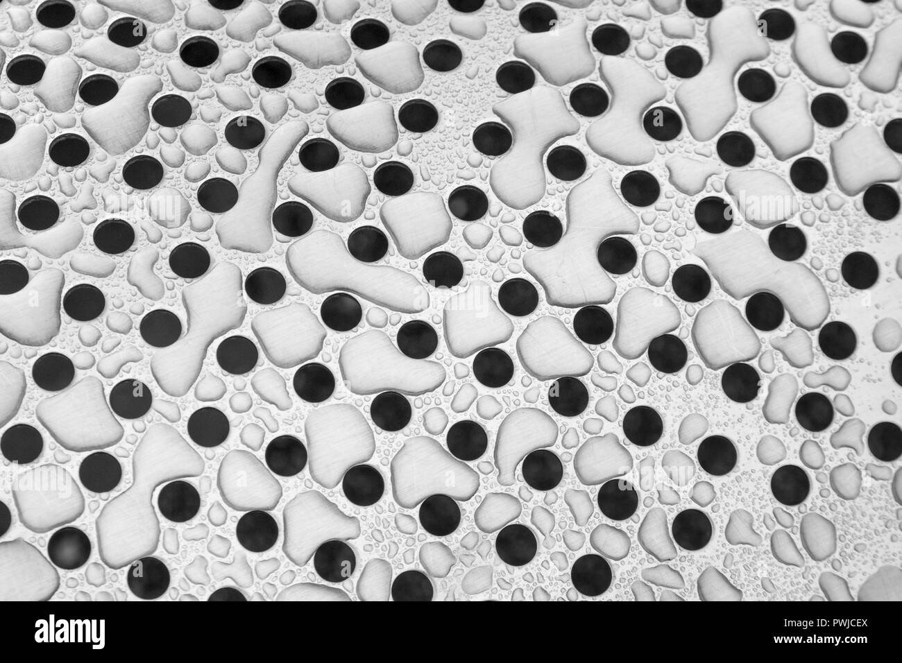Des gouttes d'eau après la pluie sur la tôle perforée en acier inoxydable. Métaphore de la trypphobie. Métal avec gouttes d'eau dessus. L'eau comme matière première. Banque D'Images