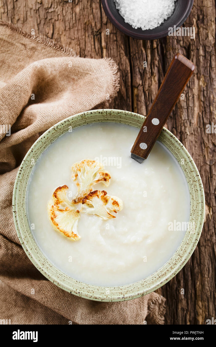 Maison douce soupe crème de chou-fleur Chou-fleur rôti garni de tranches de fleurs, servi dans un bol avec une cuillère, frais généraux photographié Banque D'Images