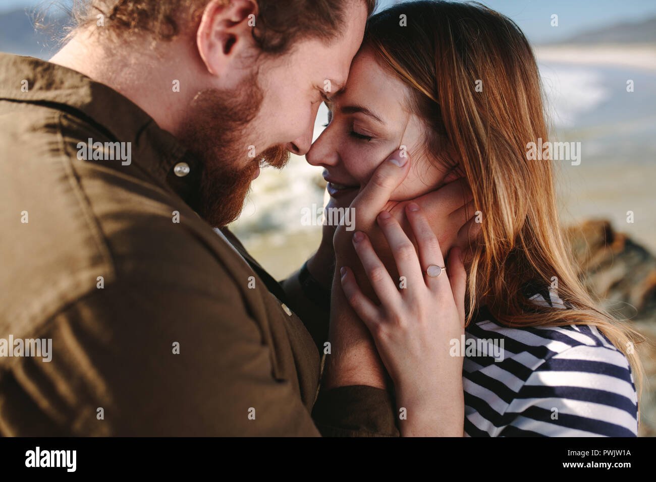 Close up of beard homme avec femme de toucher leur front à une plage. Couple romantique sur la plage. Banque D'Images