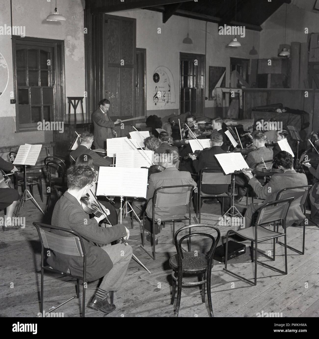 Années 1950, historique, les membres ou les joueurs d'un orchestre dirigé par le chef de village, pratiquer ensemble à l'intérieur d'une paroisse ou d'une salle communautaire, England, UK. La musique amateur a été, avec le théâtre amateur, un loisir populaire et l'activité sociale pour beaucoup d'adultes dans un sombre après-ww2 de la Grande-Bretagne. Banque D'Images