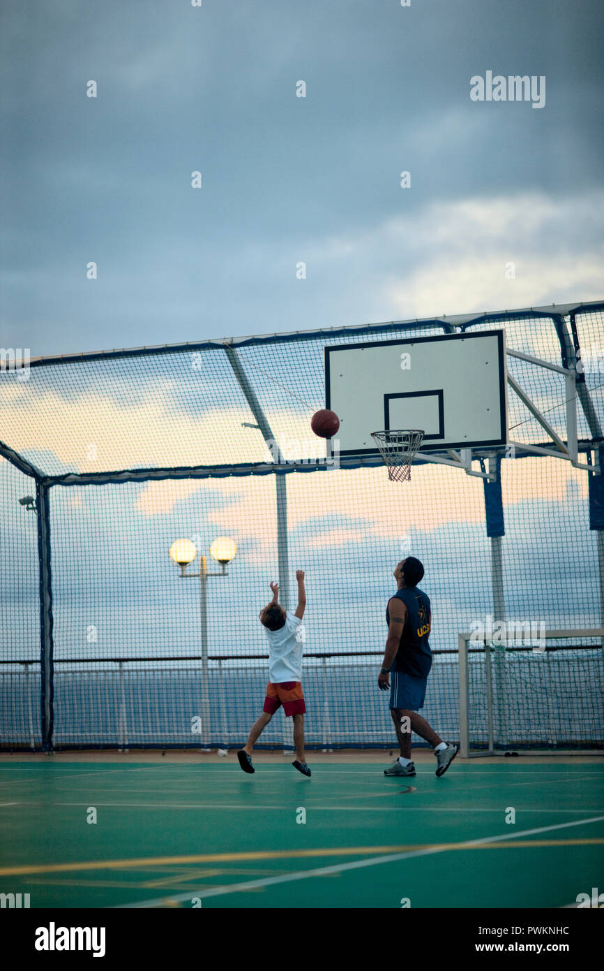 Montres homme comme un garçon jette un terrain de basket-ball à un cerceau la mer sur un terrain clos de basket-ball. Banque D'Images