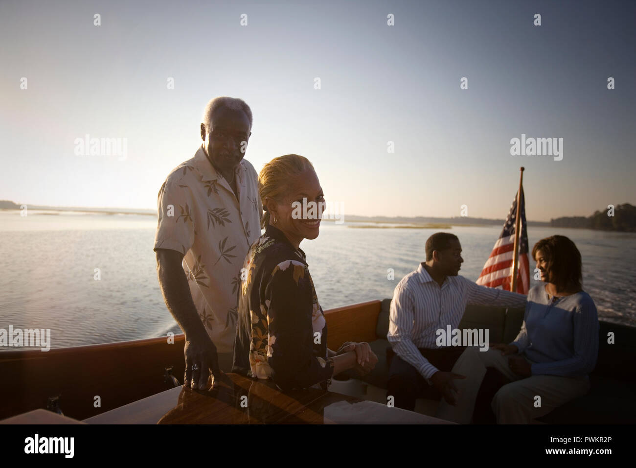 Portrait of a young couple sur un bateau avec leur mi-fils adulte et sa femme au coucher du soleil. Banque D'Images