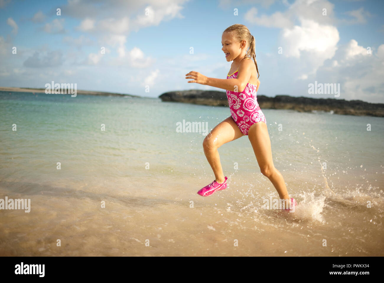 Jeune fille courir dans l'eau peu profonde sur une plage tout en portant un  maillot de bain Photo Stock - Alamy
