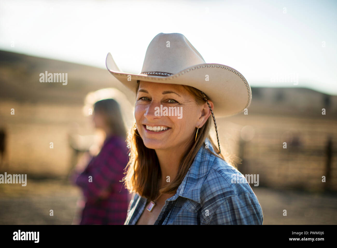 Portrait of a smiling éleveur portant un chapeau de cow-boy tandis que dehors sur le ranch. Banque D'Images
