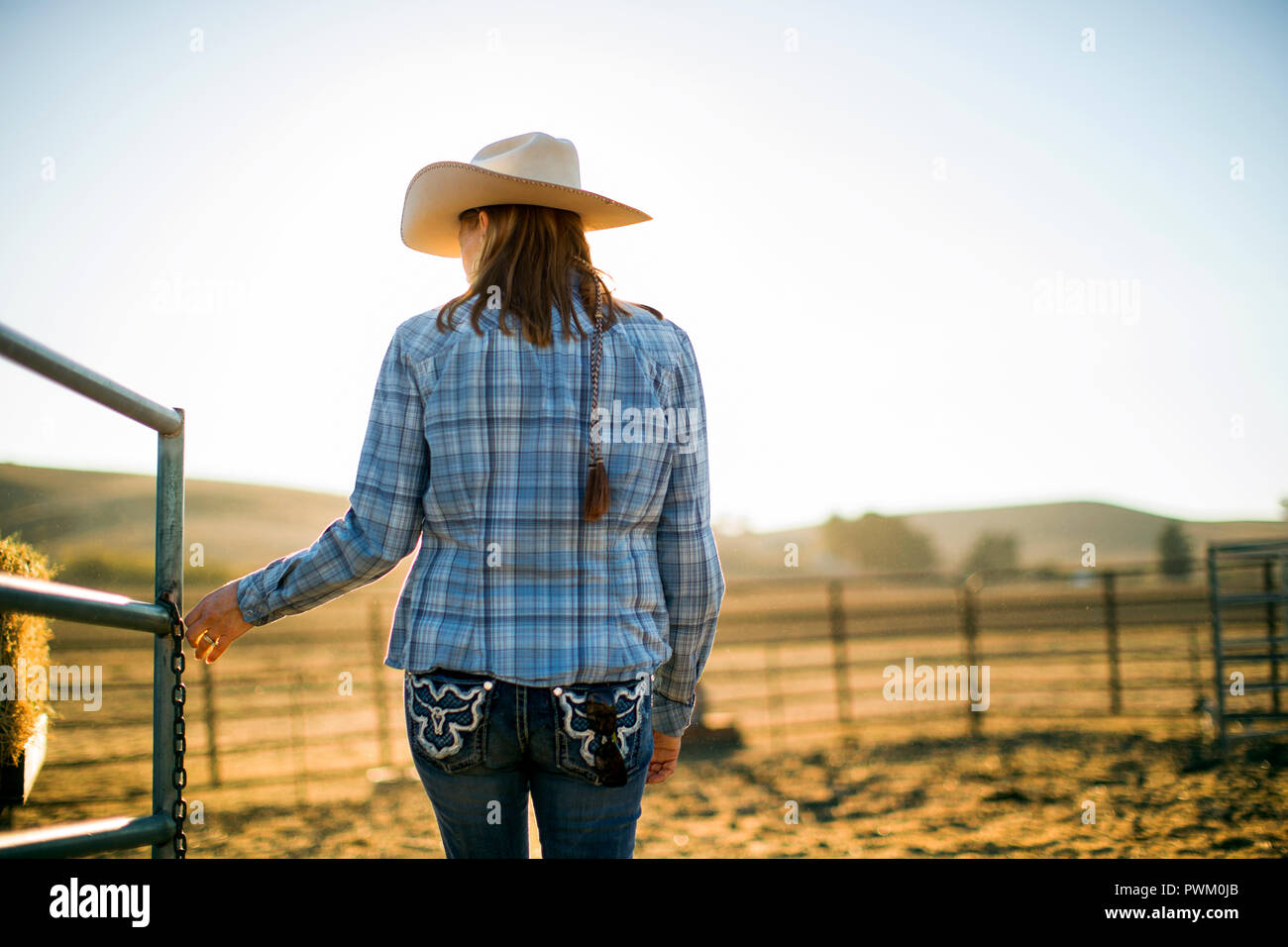 Femme du fermier portant un chapeau de cowboy ouvrir un portail sur le ranch. Banque D'Images