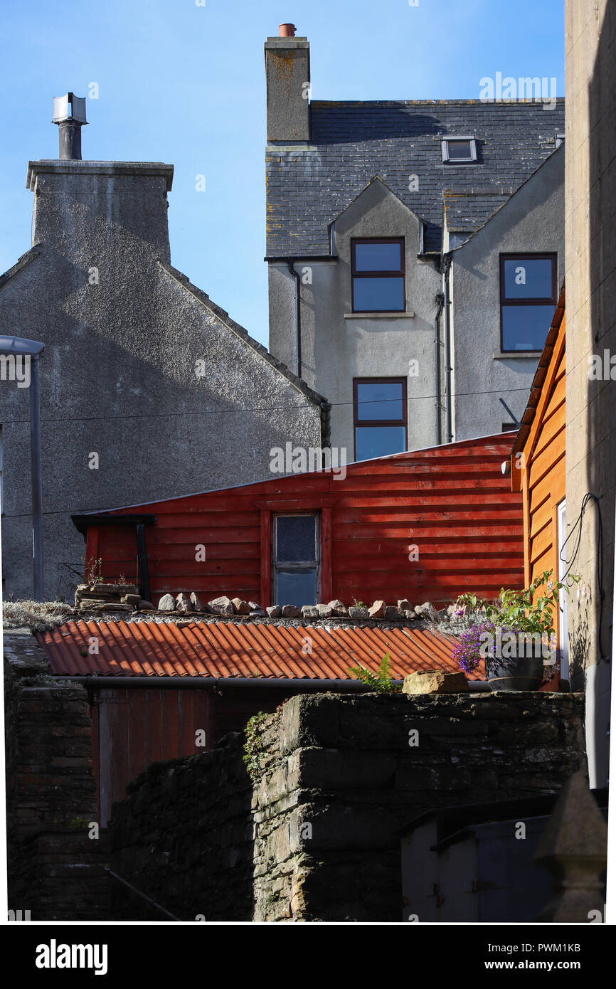 Aux couleurs rouge et d'orange cabanes dans une ville écossaise austère, Stromness, surprendre le voyageur unexpecting s'il regarde cette allée. Banque D'Images