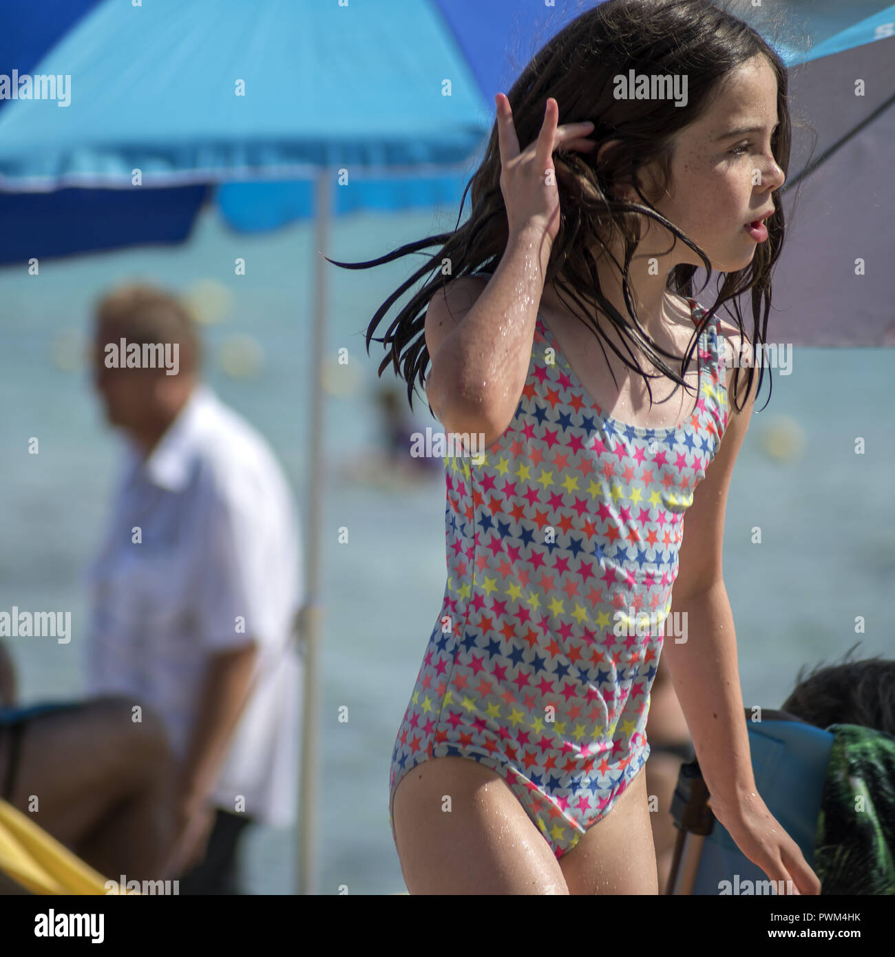 La jeune fille dans un maillot de bain humide améliore ses cheveux mouillés. Plage de Santa Giulia en Corse. Plaża Korsyce na Santa Giulia. Mokrym stroju Dziewczynka w. Banque D'Images