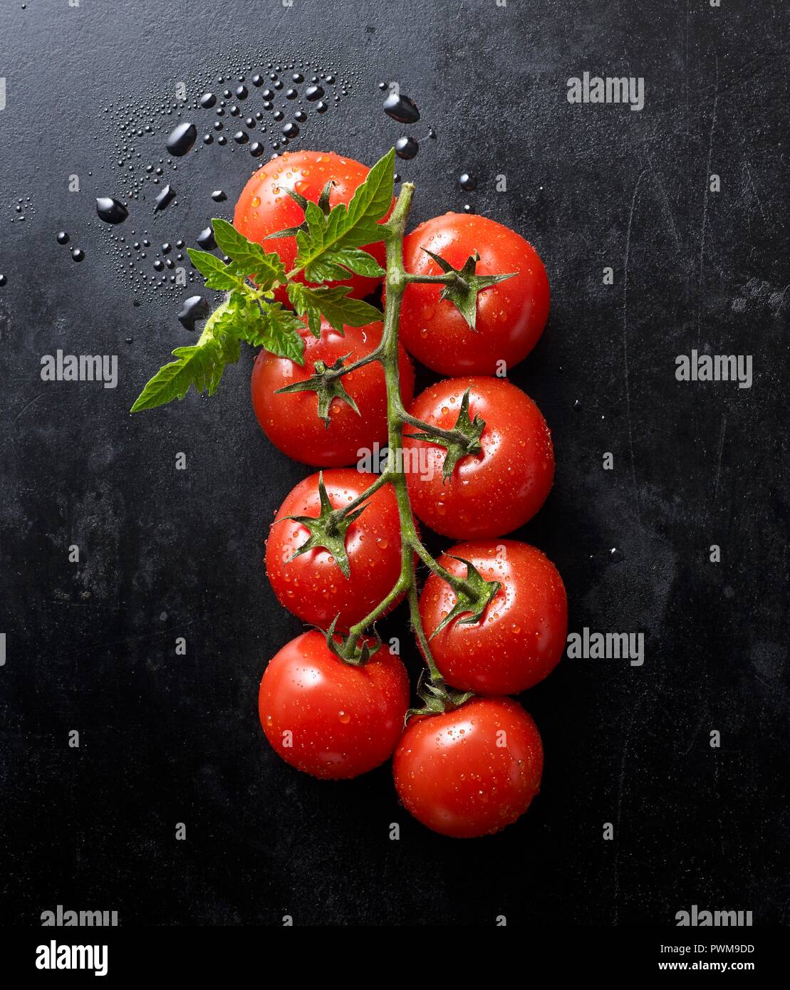 Les tomates fraîches et une feuille noire sur une plaque de cuisson Banque D'Images