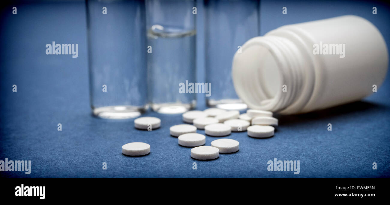 Certaines fioles médecine avec pastilllas blanc isolé sur fond bleu Banque D'Images