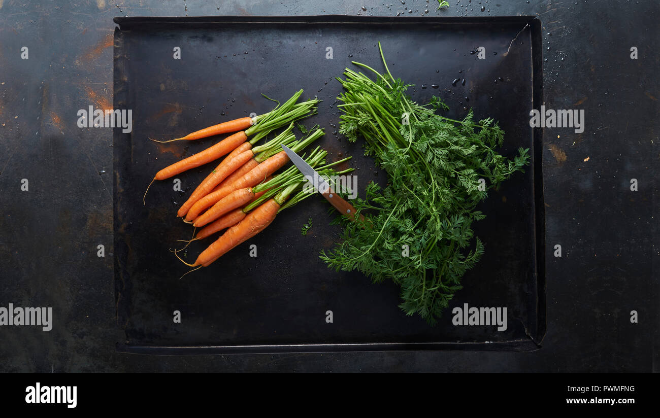 Les carottes avec les feuilles coupées sur une plaque de cuisson Banque D'Images