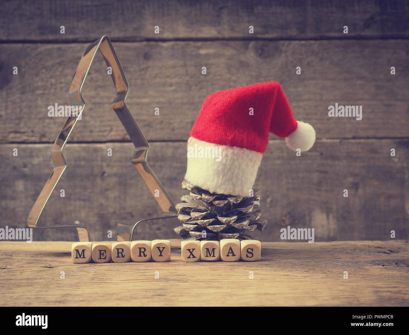 Noël arrière-plan avec un moule en forme d'arbre et une pomme de pin sur une planche en bois rustique, les mots Merry X-mas sur de petits dés en bois Banque D'Images