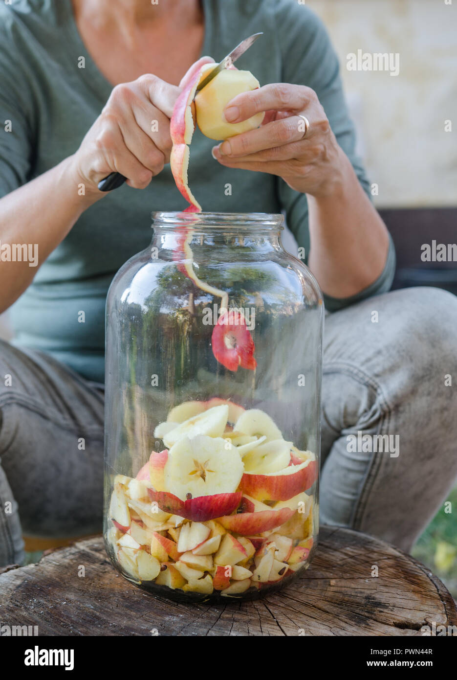 Femme fait vinaigre de pomme - Peler la pomme et la couper en une bouteille Banque D'Images