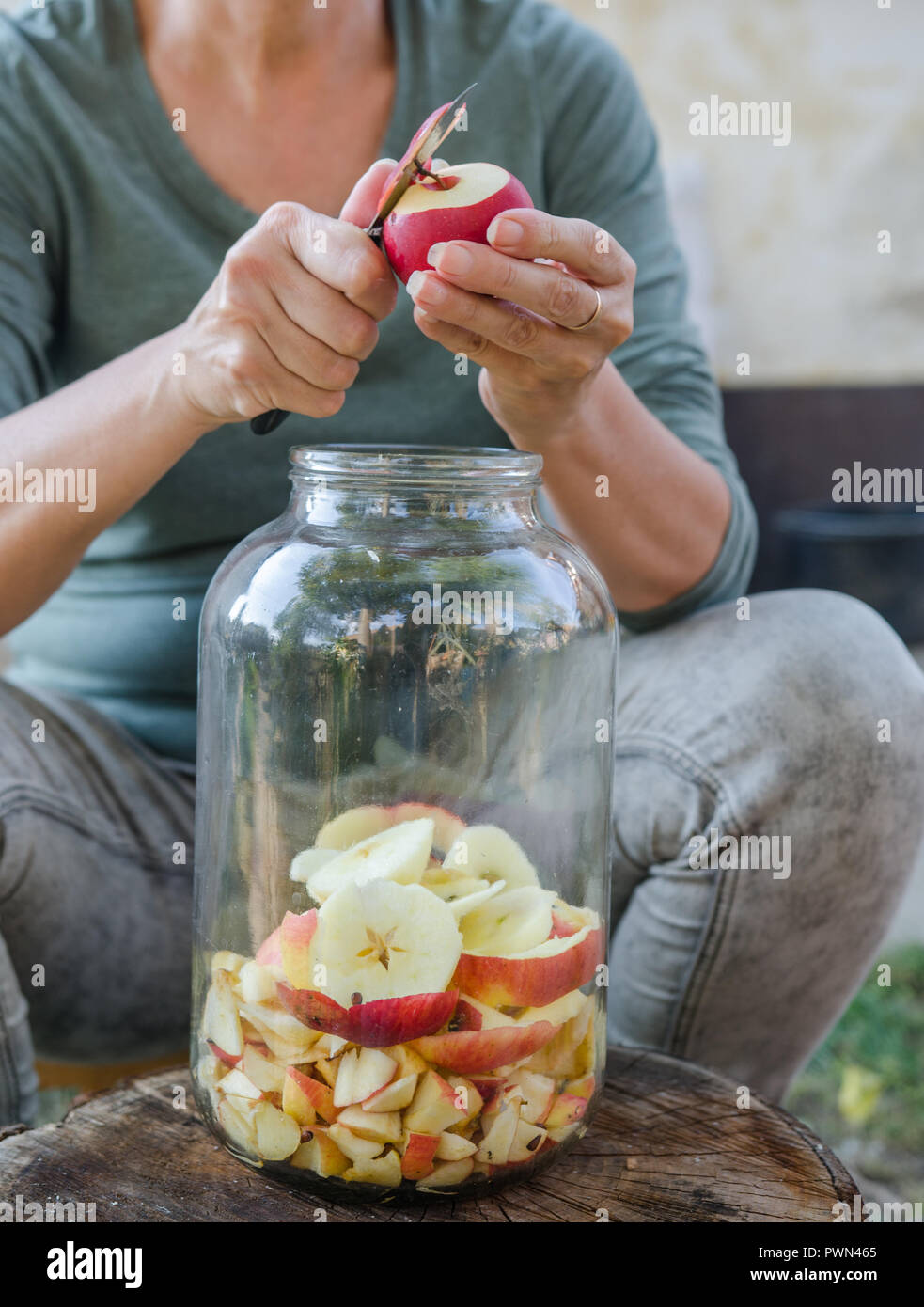 Femme fait vinaigre de pomme - Peler la pomme et la couper en une bouteille Banque D'Images