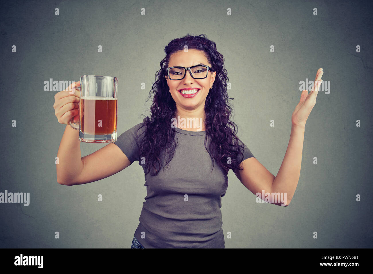 Cheerful woman holding glass mug of beer célébrant and smiling at camera Banque D'Images