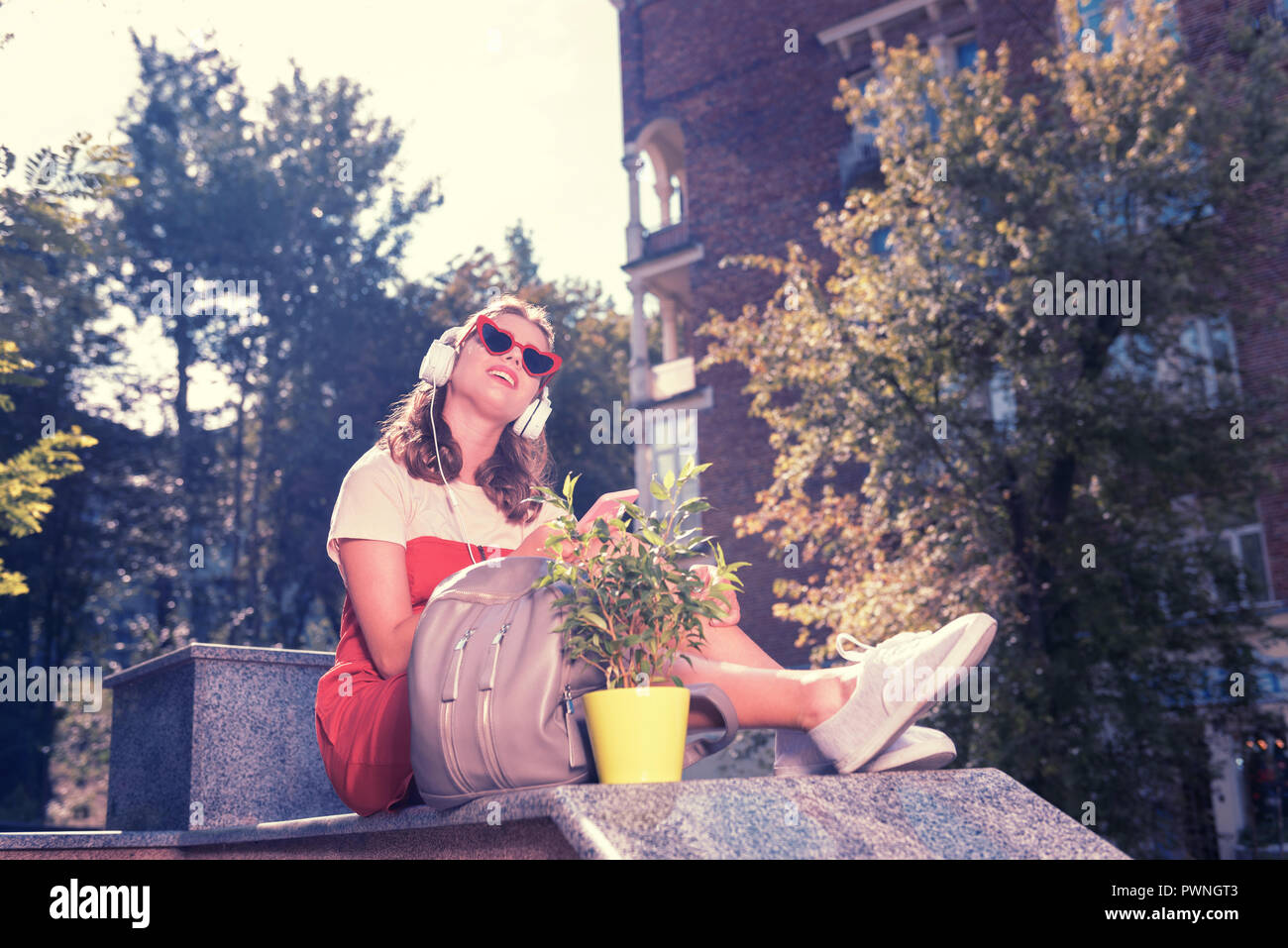 Appel femme assise dans le parc après l'achat de l'usine accueil Nouvel appartement Banque D'Images