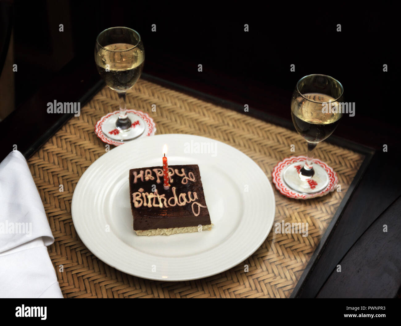 Un Petit Carre De Chocolat Gateau D Anniversaire Avec L Inscription Joyeux Anniversaire Et Une Bougie Sur Une Plaque Blanche A Cote De Deux Verres De Vin Photo Stock Alamy