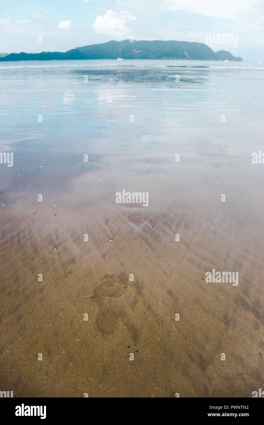 Des traces de pas dans le sable humide donnent sur l'océan Pacifique dans une baie de l'ouest de Costa Rica Banque D'Images