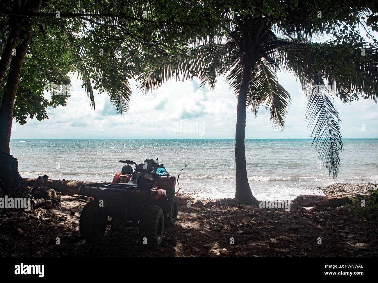 Vtt rouge garé sur un roadtrip de la côte Pacifique du Costa Rica - l'eau turquoise, palmier et plage vide Banque D'Images