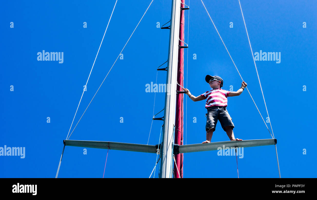 Un enfant de 7 ans, l'escalade à un mât d'un bateau à voile, Clifton, Union island, Petites Antilles, Antilles Banque D'Images