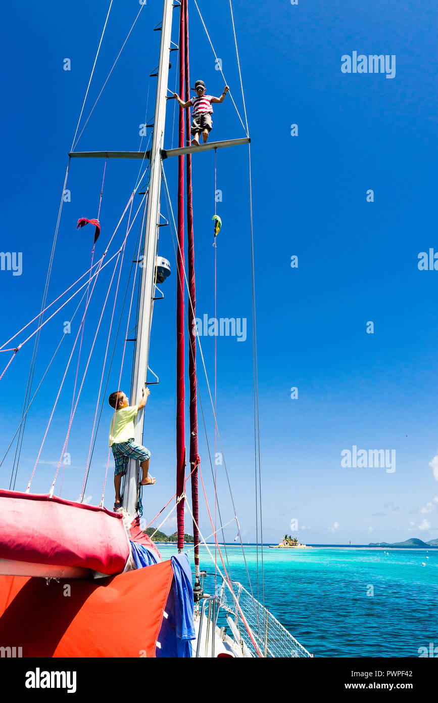 Un enfant de 7 ans, l'escalade à un mât d'un bateau à voile, Clifton, Union island, Petites Antilles, Antilles Banque D'Images