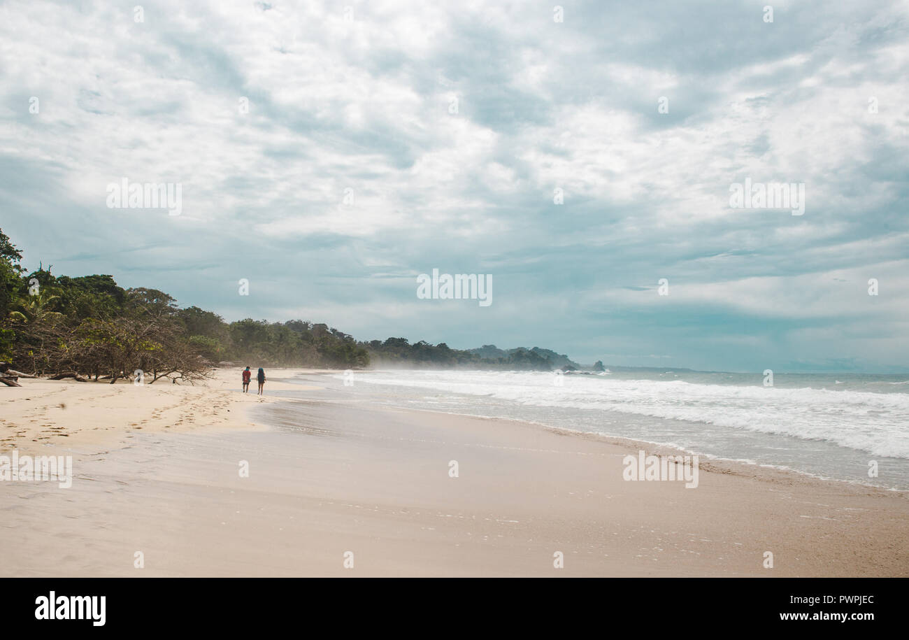 Deux voyageurs randonnée marche sur la grande plage de sable blanc de Red Frog Beach, une île des Caraïbes au large de Panama Banque D'Images