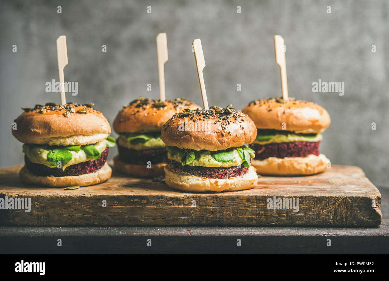 Télévision à jeter des hamburgers végétaliens sains avec quinoa galettes de betteraves, choux vert et crème d'avocat sur planche de bois, mur gris à l'arrière-plan. Végétarien, Banque D'Images