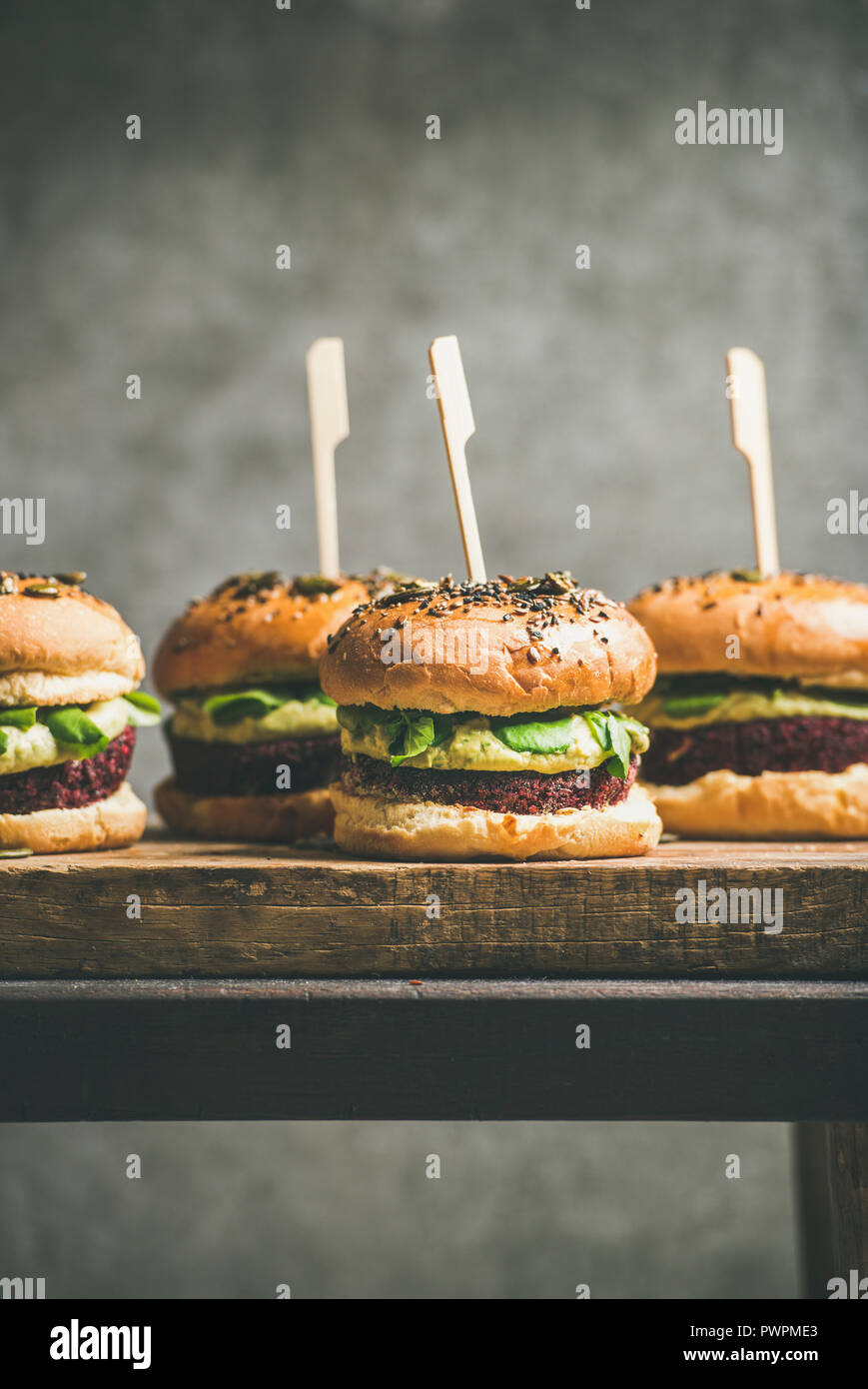 Télévision à jeter des hamburgers végétaliens sains avec quinoa galettes de betteraves, choux vert et crème d'avocat sur planche de bois, mur gris à background, selective fo Banque D'Images
