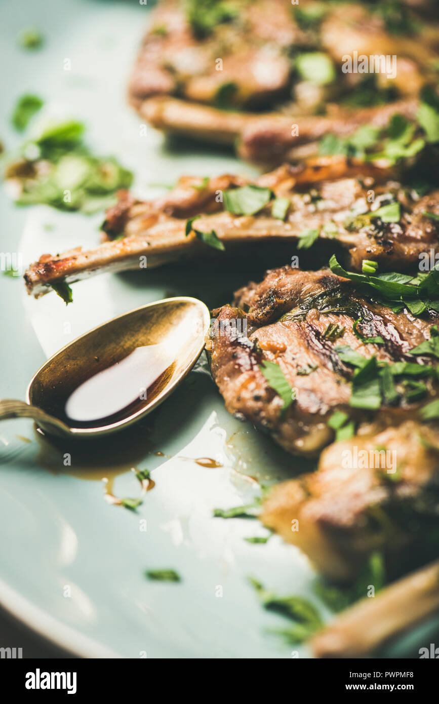Dîner de la viande. Côtes d'agneau grillées avec sauce persil vert et bleu dans le plat de service sur table béton background, selective focus, vertical compositio Banque D'Images