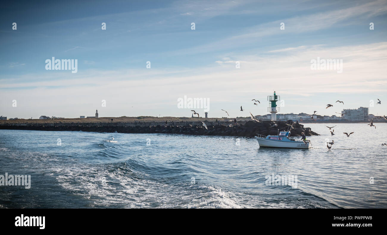 Saint Gilles Croix de Vie, France - 16 septembre 2018 : petit bateau de pêche entrant dans le port accompagné de mouettes sur une journée d'été Banque D'Images