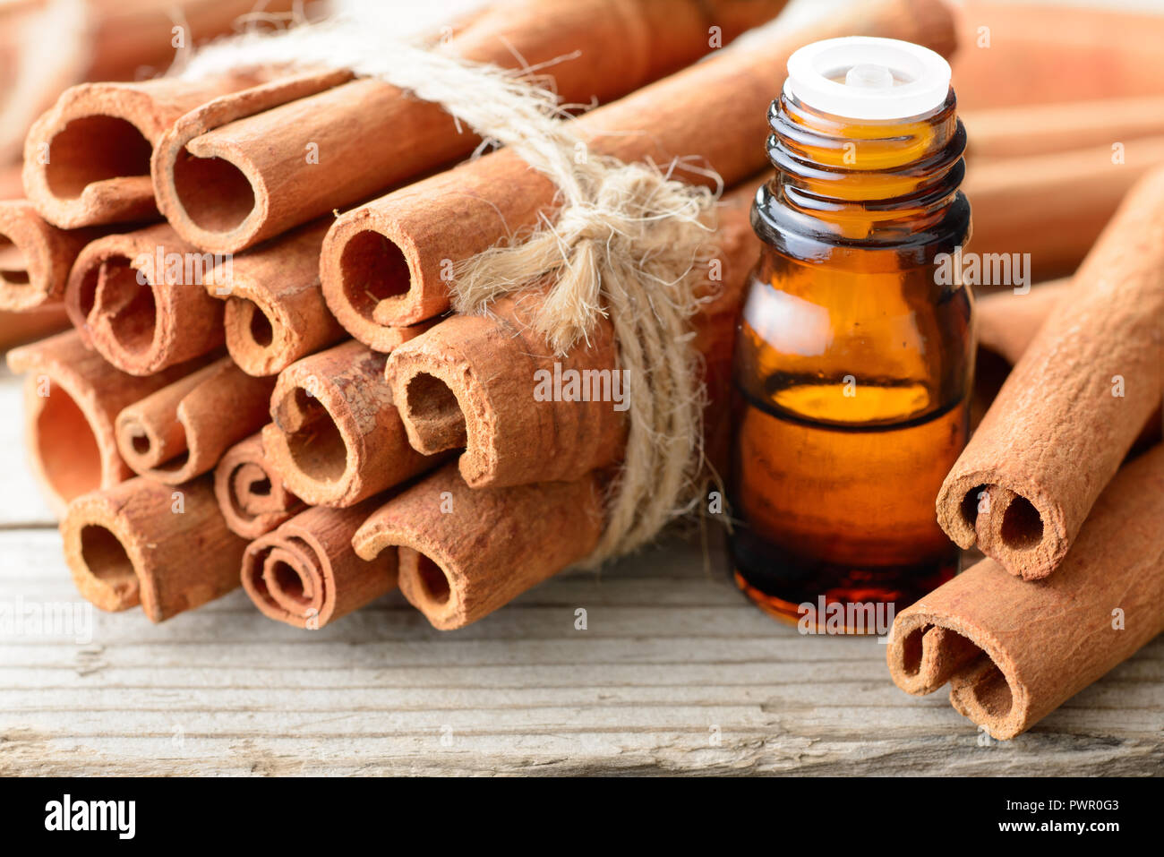 L'huile de cannelle et des bâtons de cannelle sur la planche de bois Banque D'Images