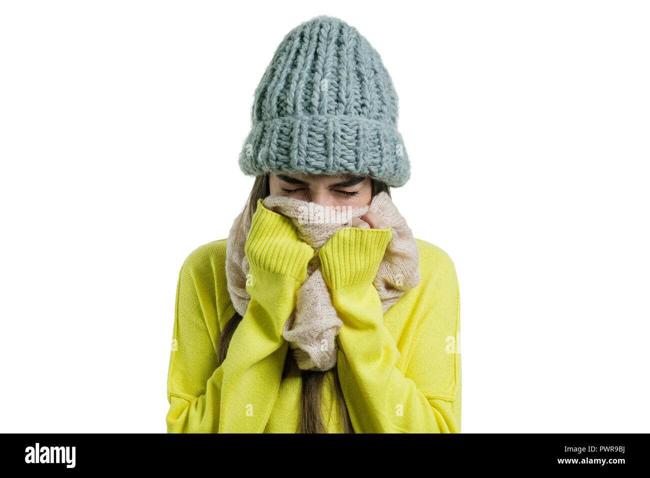 Une femme froide, dans un chapeau tricoté écharpe, éternue, couvert sa  bouche avec ses mains Photo Stock - Alamy