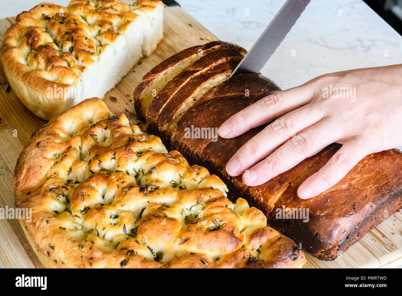 Image main de femme libre de couper du pain frais fait maison sur compteur de cuisine Banque D'Images