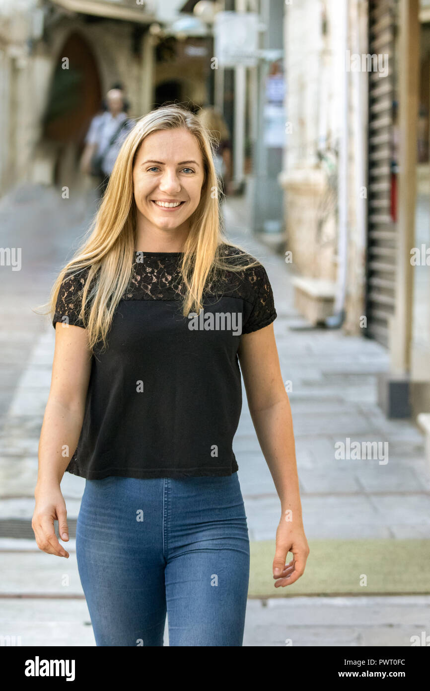 Portrait d'une jeune femme blonde en Pologne, 24 ans, la marche de l'appareil photo à l'extérieur, souriant, heureux. Banque D'Images
