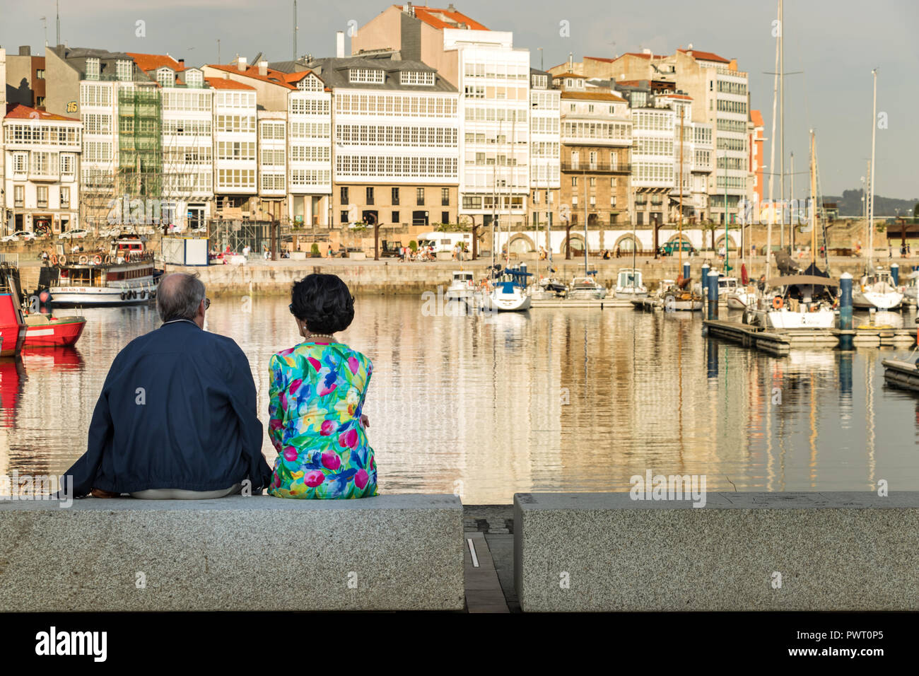 La Corogne, Espagne - Juillet 13th, 2018 : A young couple autour de 60 ans sont assis à la vue depuis le port dans l'après-midi. Banque D'Images