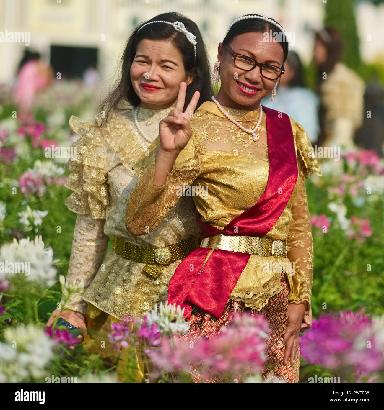 Deux femmes thaïlandaises en costume traditionnel à un événement commémoratif pour le Roi Bhumipol Adulyadej à Bangkok, Thaïlande, un clignotant l'omniprésent V-sign Banque D'Images