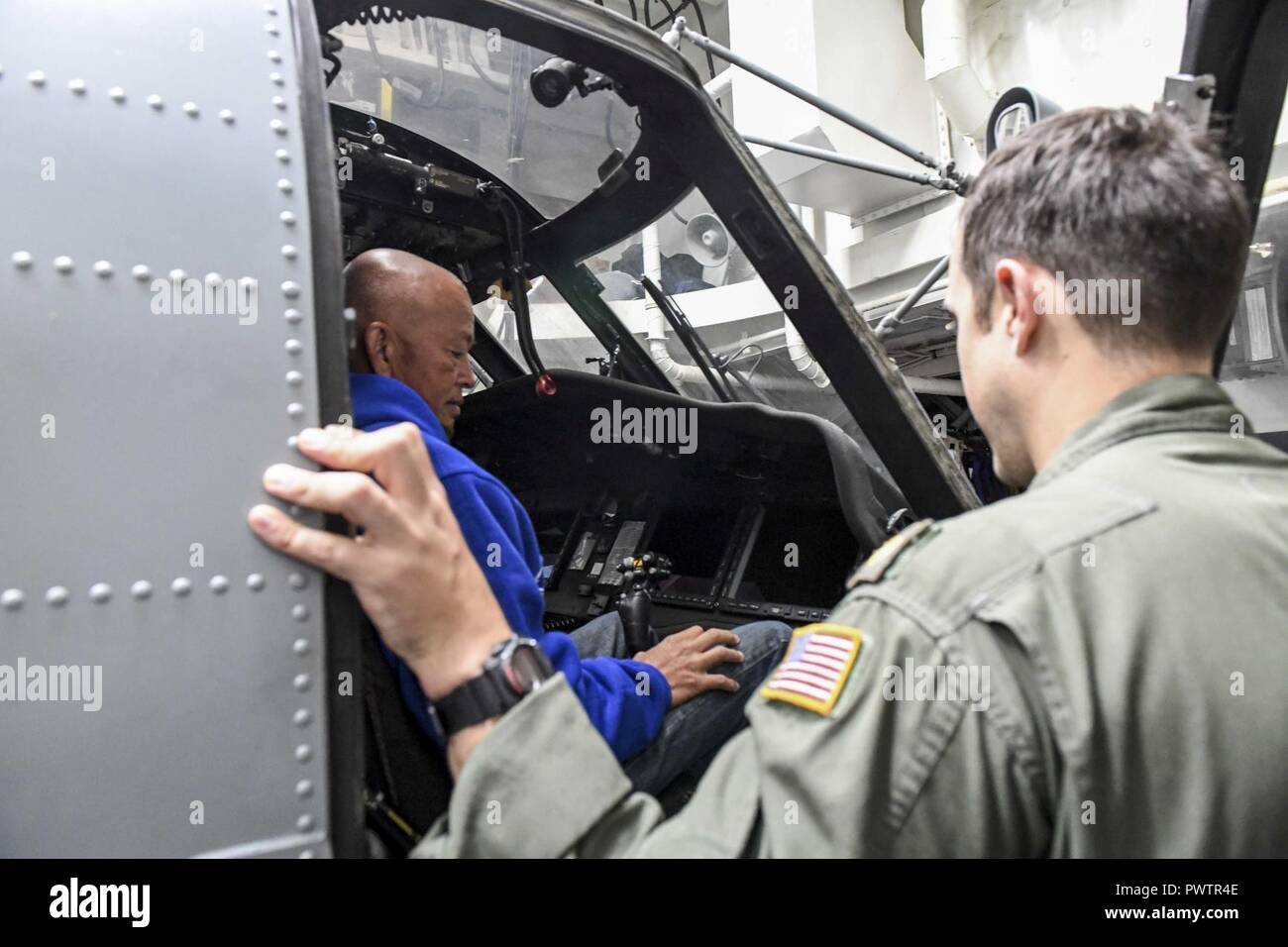 Océan Pacifique (20 juin 2017) Le lieutenant Cmdr. Andrew Poreda, un pilote responsable de l'Escadron grève maritime des hélicoptères embarqués (HSM) 78, permet aux amis et à la famille des membres de l'équipage à bord de la classe Arleigh Burke destroyer lance-missiles USS Wayne E. Meyer (DDG 108) de s'asseoir dans le cockpit d'un MH-60R Sea Hawk attaché à un tigre HSM-78 au cours de croisière. La Marine américaine a patrouillé les Indo-Asia-Pacifique couramment pour plus de 70 ans la promotion de la paix et la sécurité régionales. ( Banque D'Images