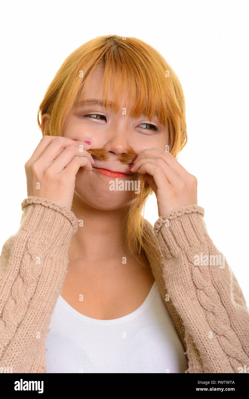 Young Asian woman smelling ses cheveux tout en regardant ailleurs Banque D'Images