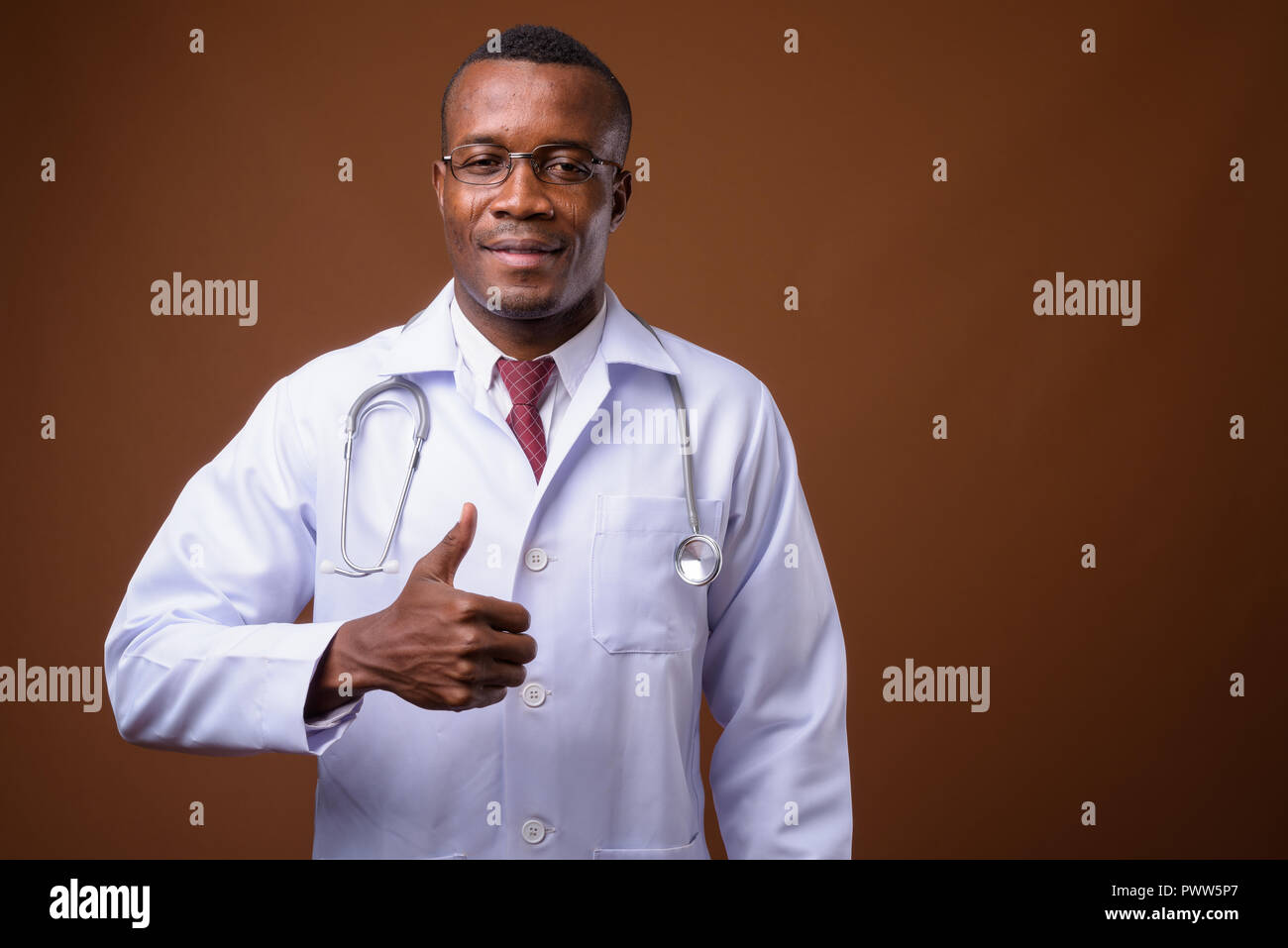 Portrait de jeune homme africain médecin contre fond brun Banque D'Images